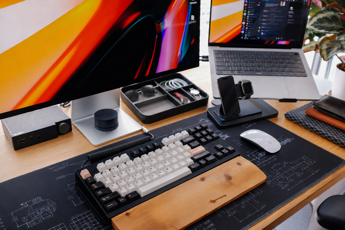 Desk setup with coiled keyboard cable, organizer tray, and 3-in-1 wireless charging stand